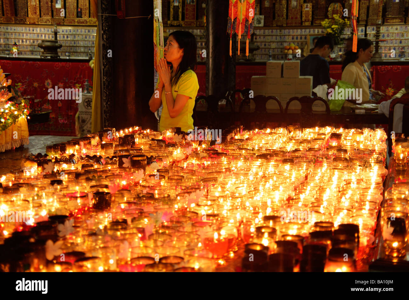 Donna orante e candele all'interno di Giac Lam Pagoda a Saigon Ho Chi Minh City Vietnam Foto Stock