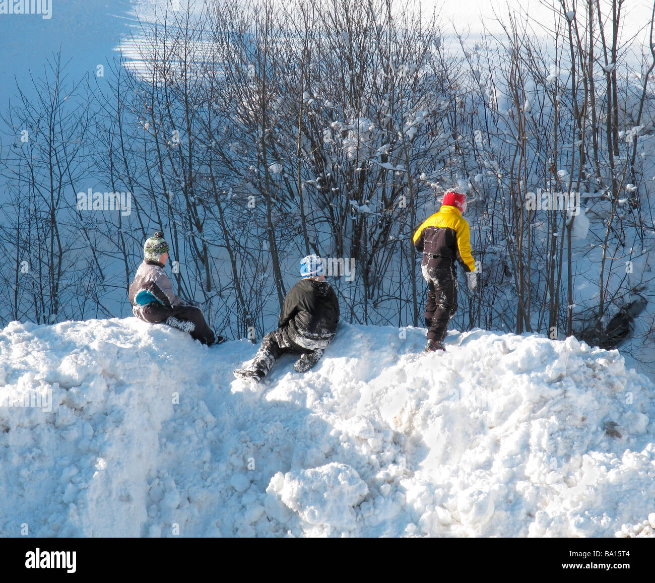 Tre bambini che giocano nel cumulo di neve Foto Stock