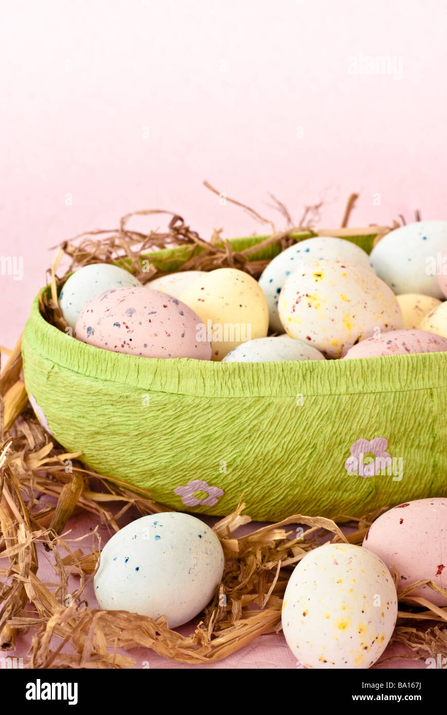 Color pastello mini uova di Pasqua in cartapesta uova a forma di contenitore con paglia, su una pianura color rosa pallido sfondo Foto Stock