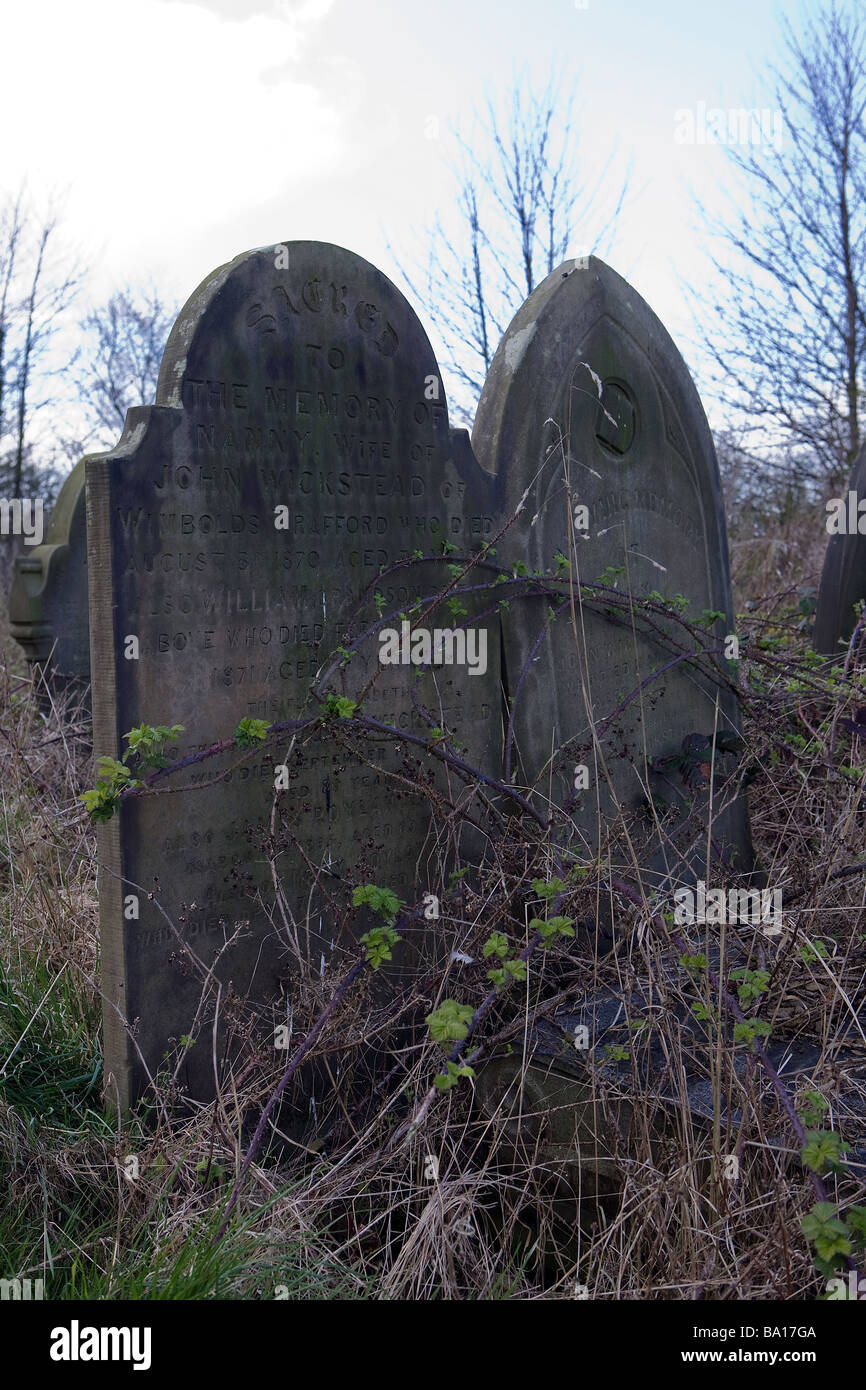 Vista attraverso un grave yard che mostra la Tomba Infestata da Erbacce le pietre a St Mary's Church, Thornton-le-Mori, Cheshire Foto Stock