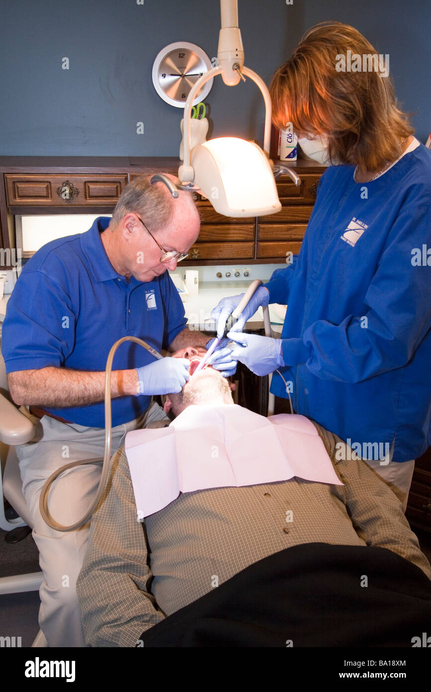 Dentista e assistente di trattare un paziente in una poltrona del dentista. Foto Stock