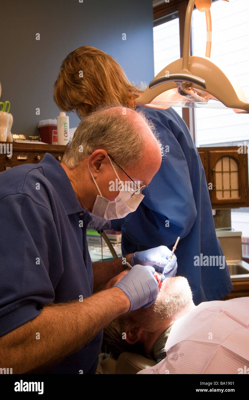 Dentista e assistente di trattare un paziente in una poltrona del dentista. Foto Stock