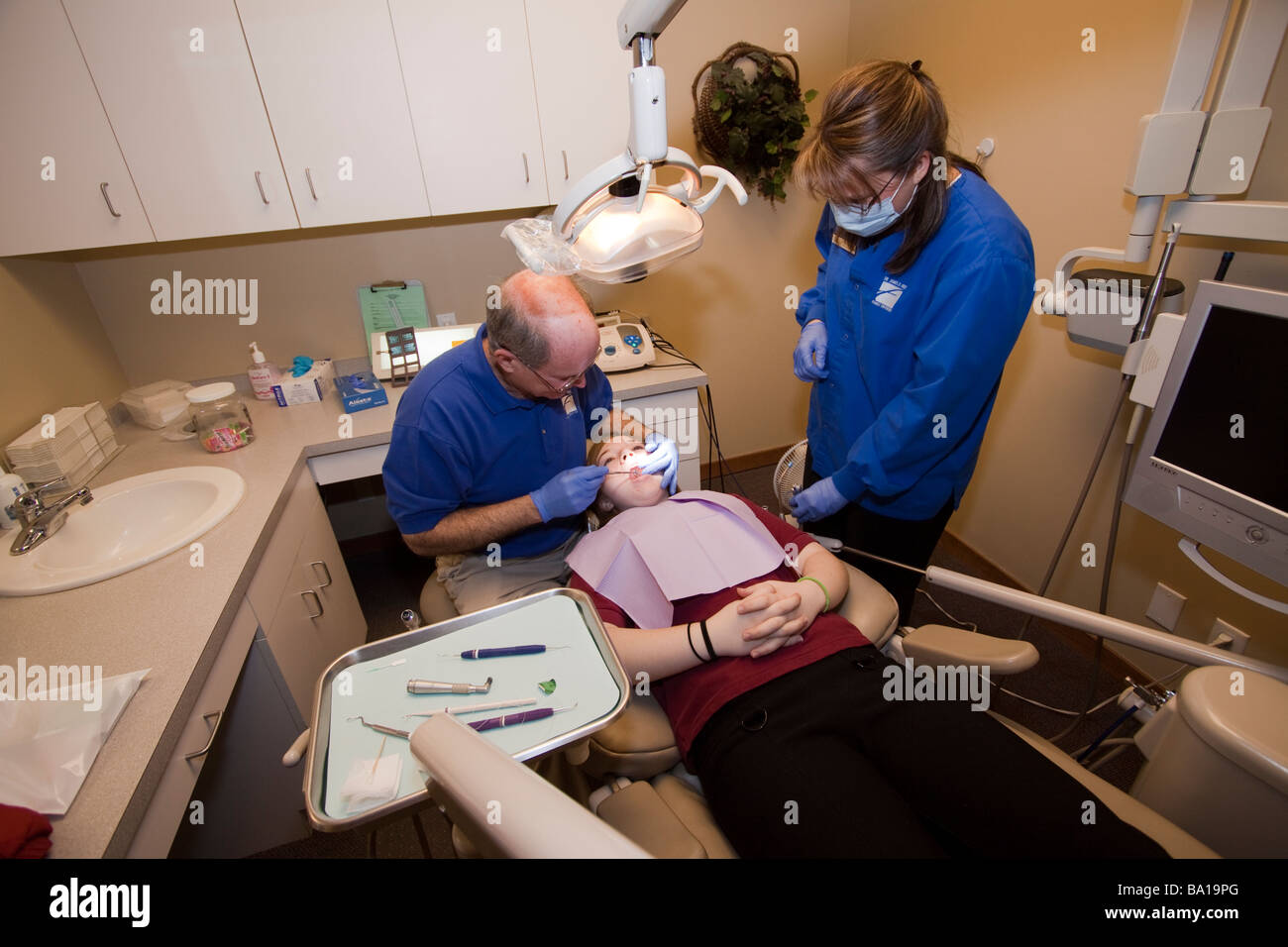 Dentista e igienista dentale il trattamento di un paziente giovane. Foto Stock