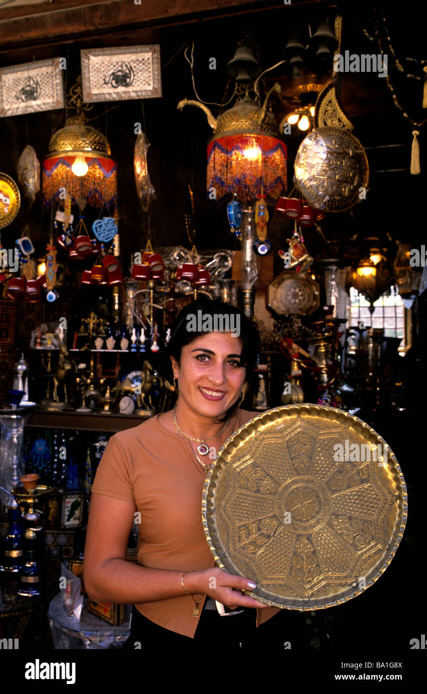 Una femmina di merchant tenendo un vassoio di rame al di fuori del suo negozio di souvenir a Byblos Città Vecchia, Libano Foto Stock
