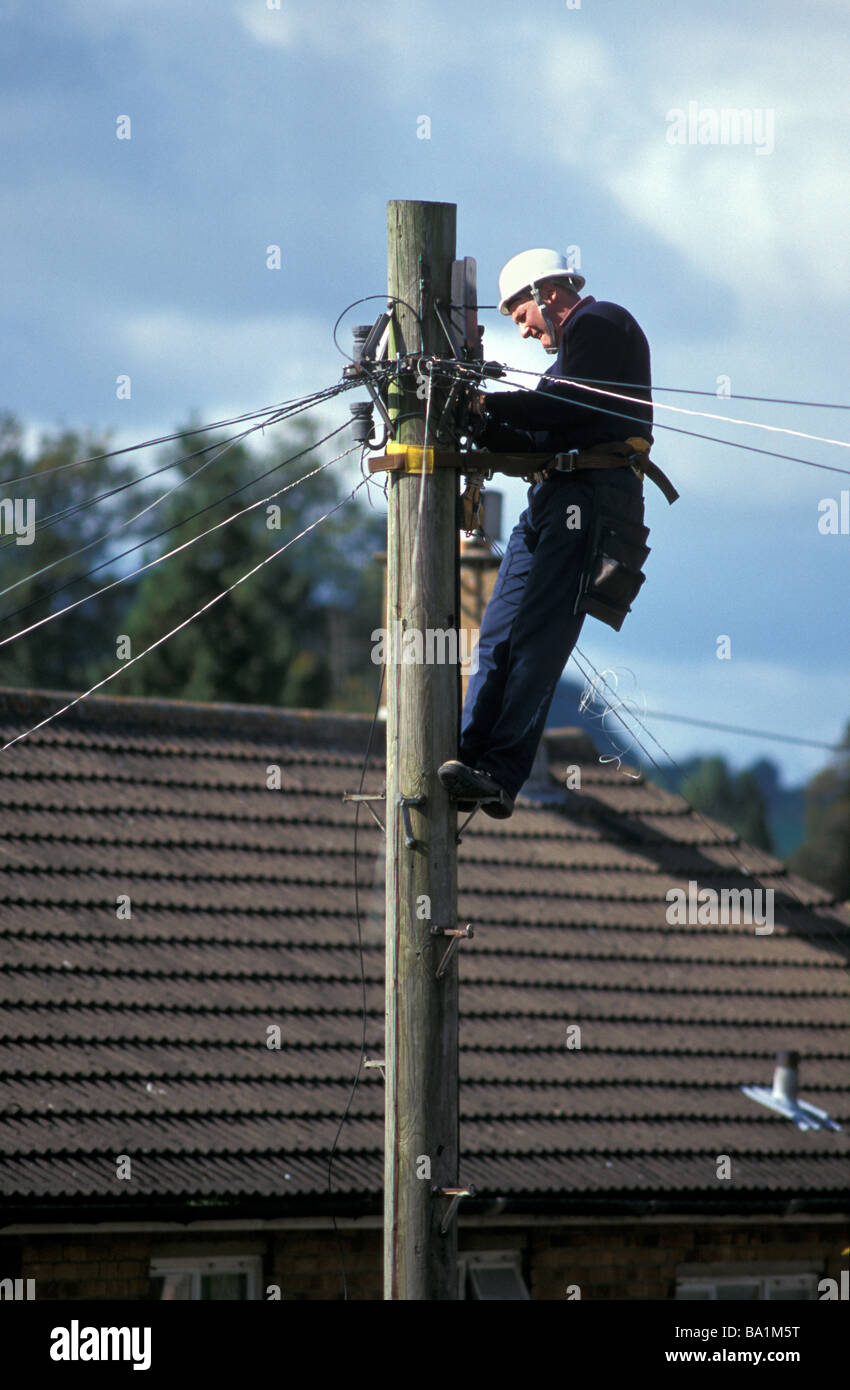 British ingegnere delle telecomunicazioni la riparazione di linea telefonica alla sommità di un palo del telegrafo Stroud Gloucestershire in Inghilterra Foto Stock