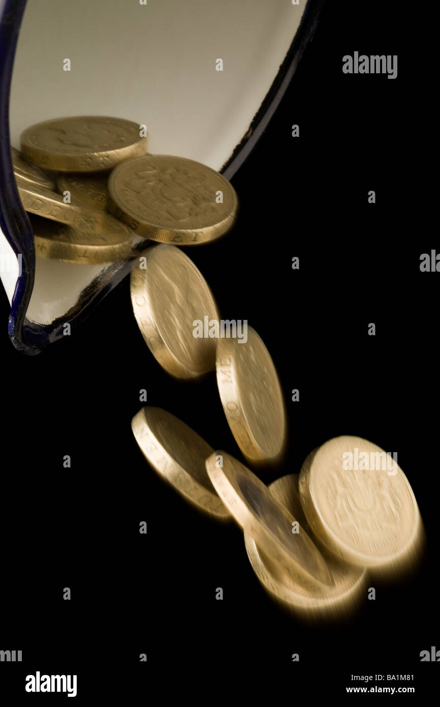 Una libbra e due monete sterlina versando al di fuori di un bricco di smalto Foto Stock