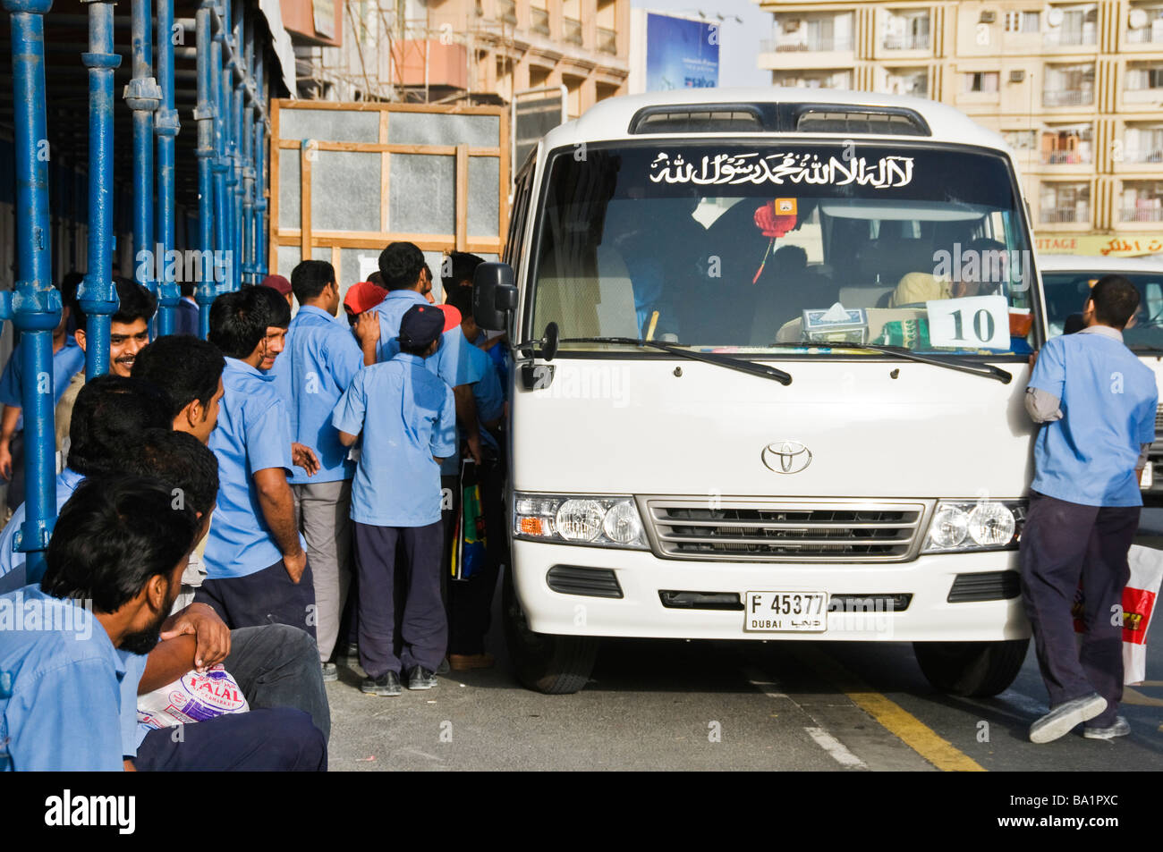 I lavoratori stranieri a salire su un autobus dopo una giornata di lavoro di Dubai EMIRATI ARABI UNITI Foto Stock