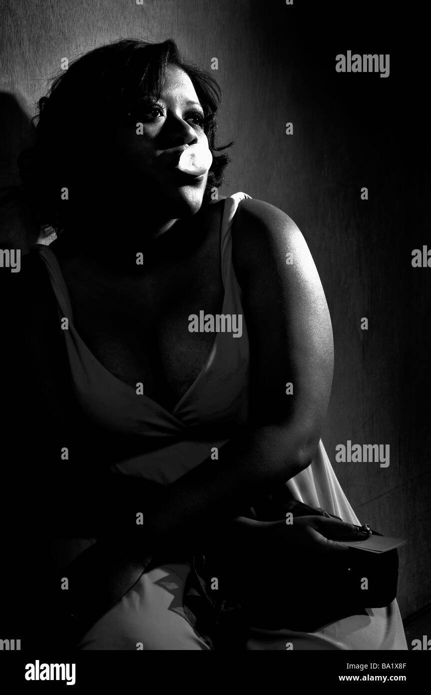 Immagine in bianco e nero di femmina nero appoggiato contro una parete a sognare di tempi migliori Foto Stock