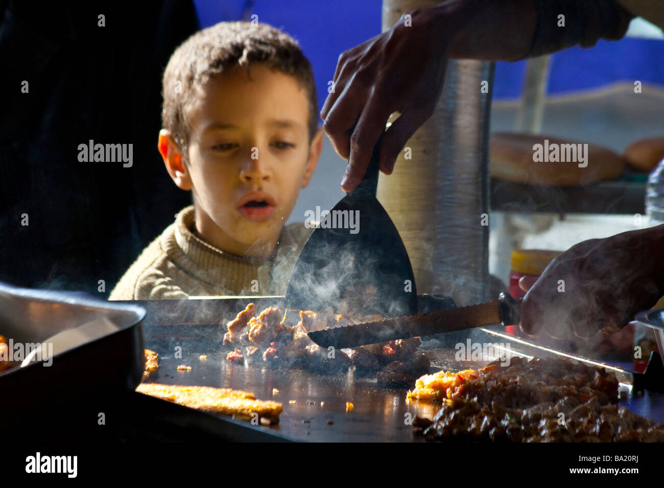 Ragazzo marocchino a guardare come la carne è preparato in Fez Marocco Foto Stock