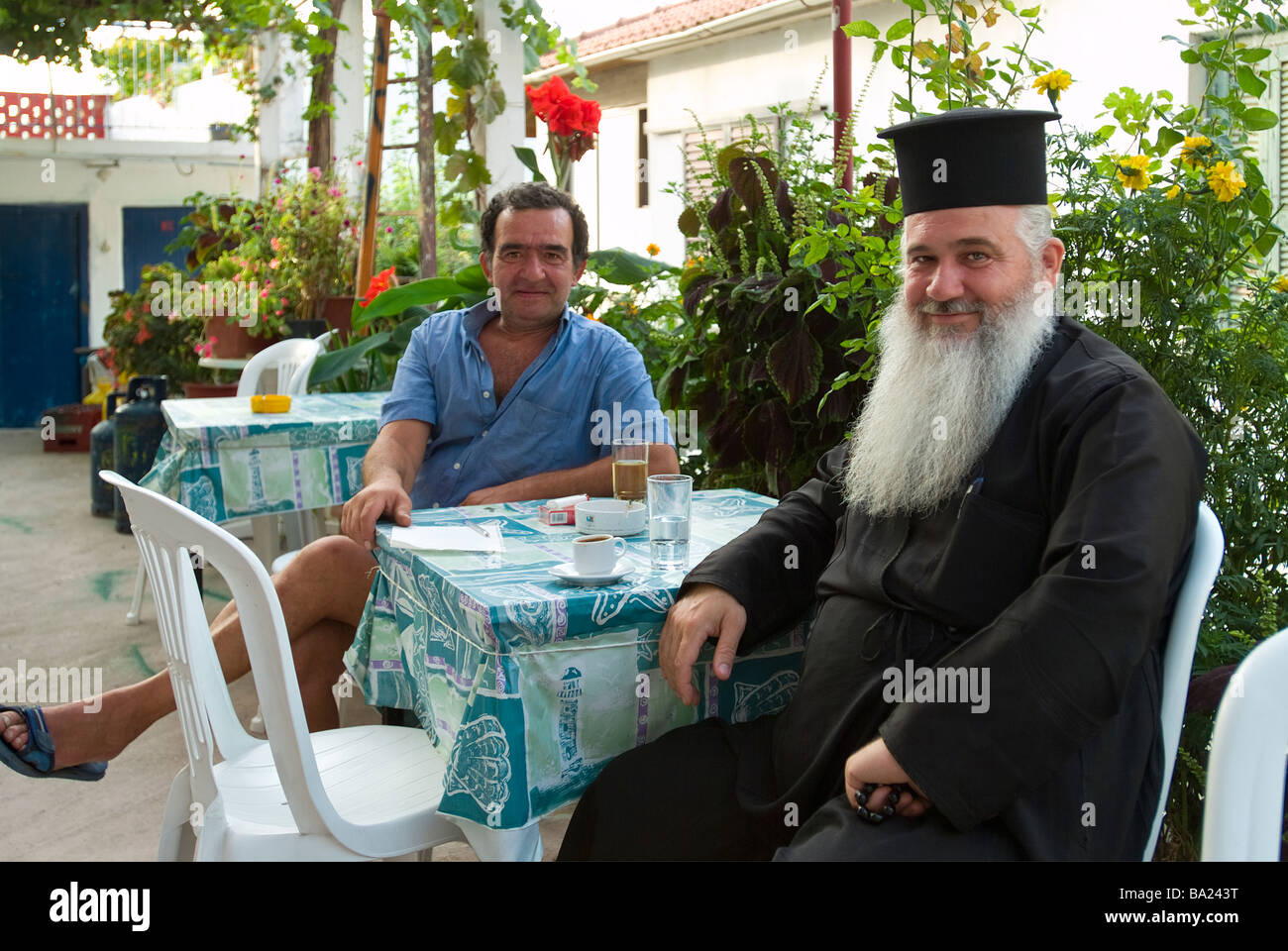 Sacerdote greco nel rilassante bar con locale, Poros village, Lefkada, isole Ionie, Grecia. Foto Stock