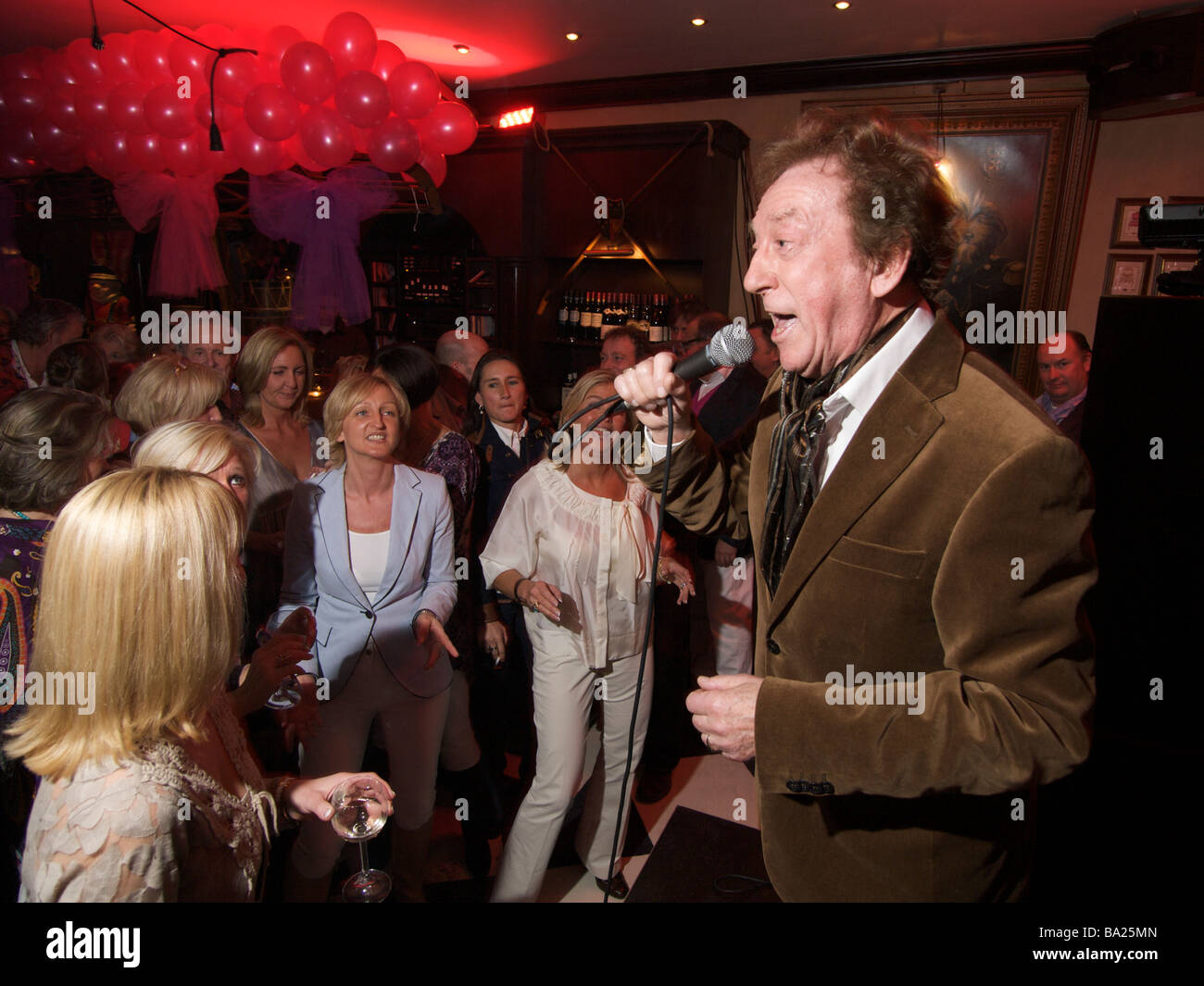 Il 78-enne crooner Harry cantare ad un party in un bar con donne che danzano e avente una buona volta Foto Stock