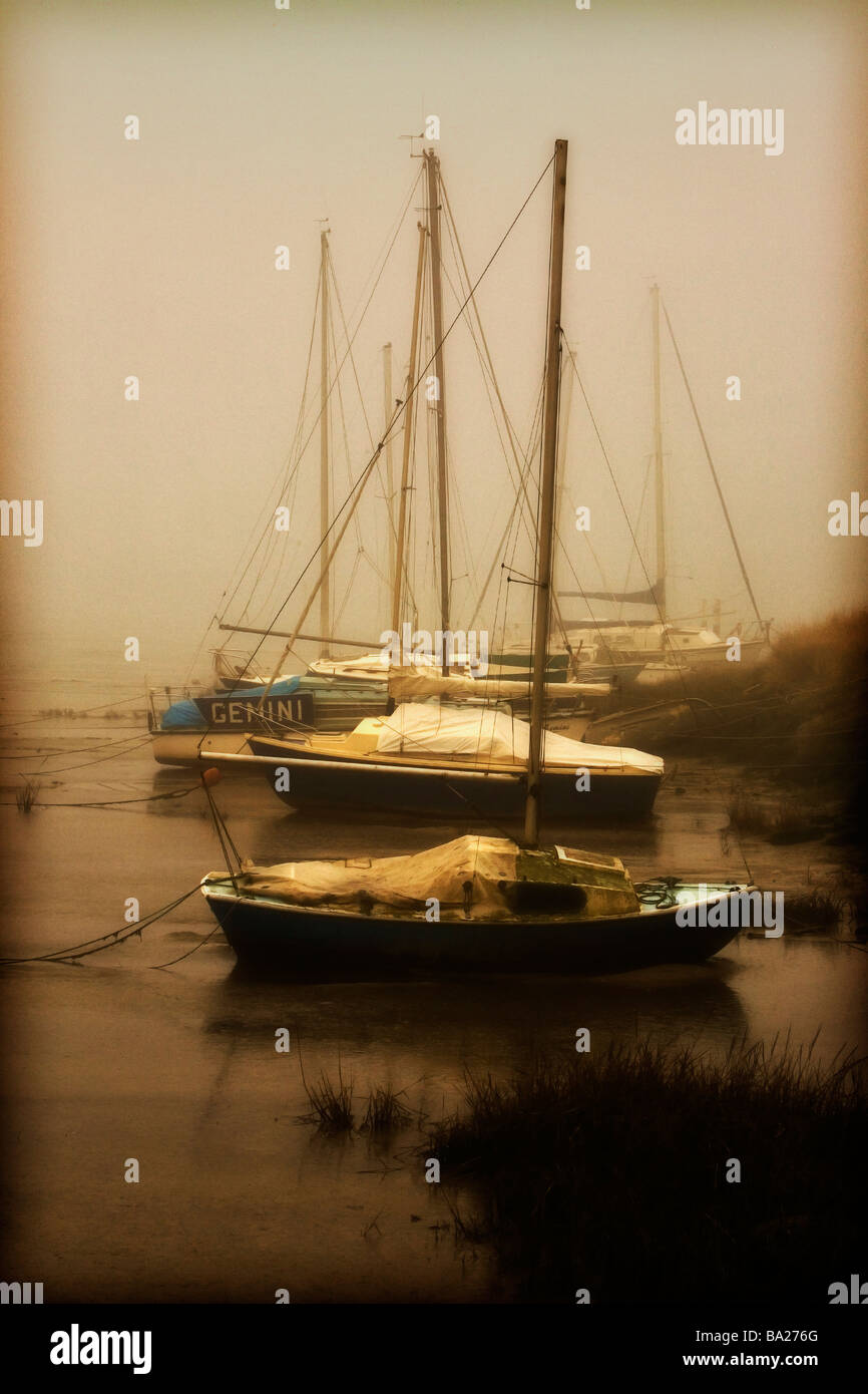 Barche a vela spiaggiata nella nebbia su una banca di fango con la marea out Foto Stock