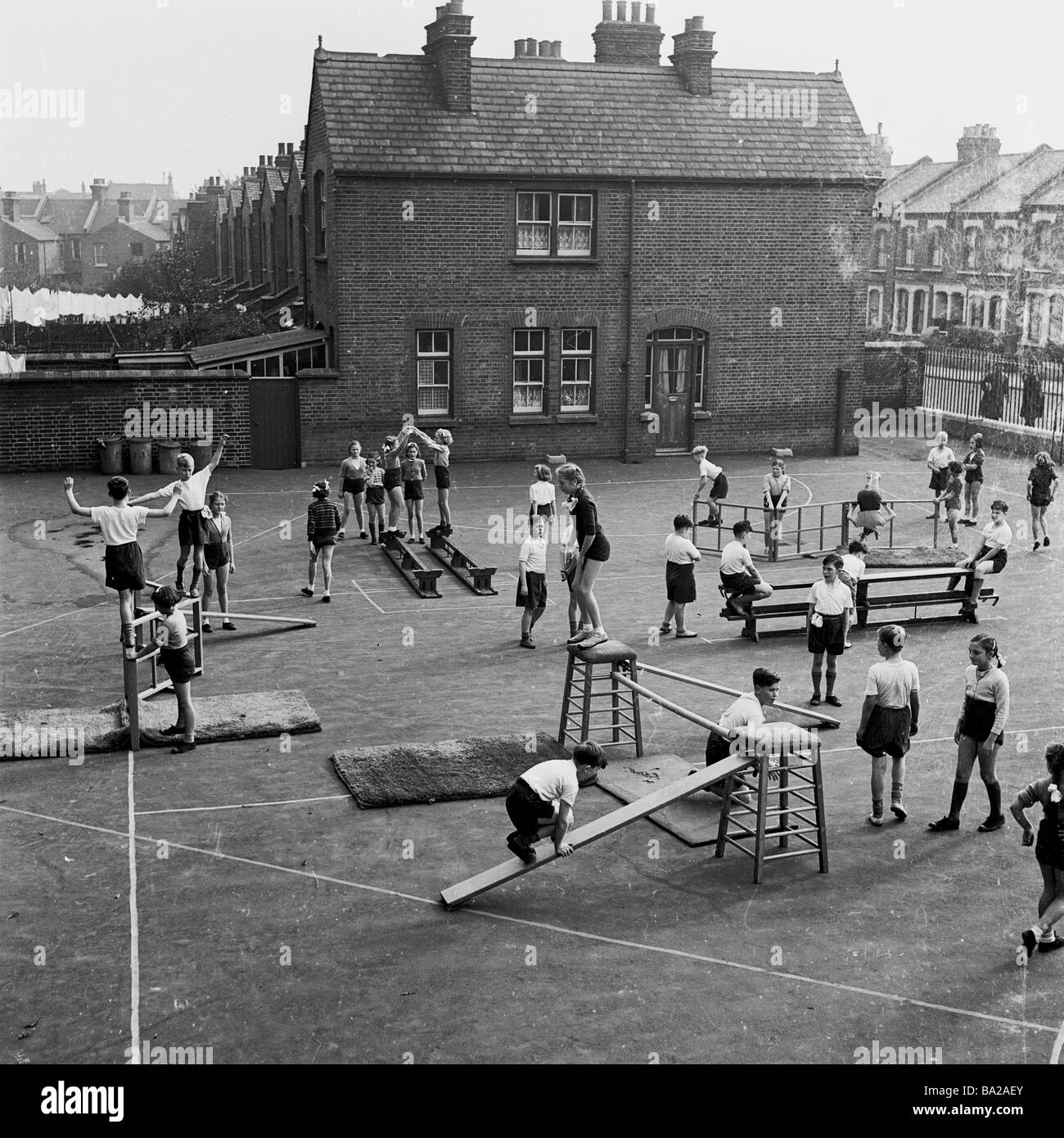 1950s, bambini storici e giovani che hanno una classe di educazione fisica tradizionale (PE) in un campo di scuola primaria interna, Londra, Inghilterra, Regno Unito. Foto Stock