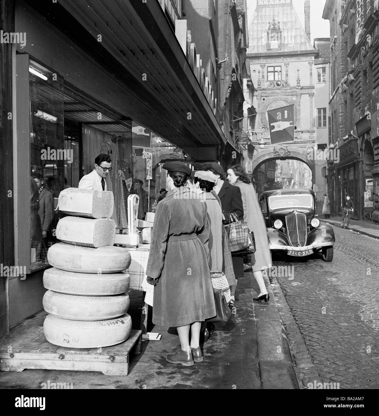 1950s, storico, acquirenti francesi di sesso femminile in uno studio di strada laterale le grandi fette rotonde di formaggio in vendita all'esterno sul marciapiede, Rouen, Francia, Foto Stock