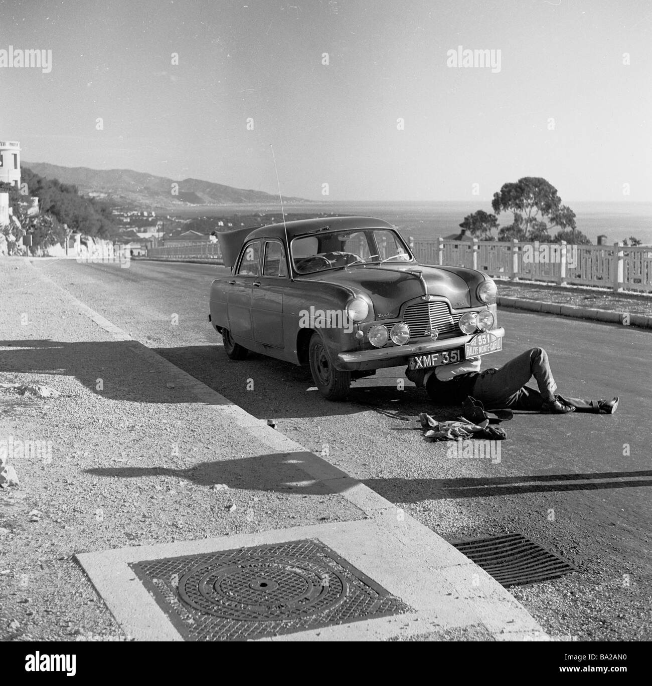 1952, storica, concorrente, no 331, nel Rally di Montecarlo, sotto la sua vettura Zephyr su una strada costiera francese. Foto Stock