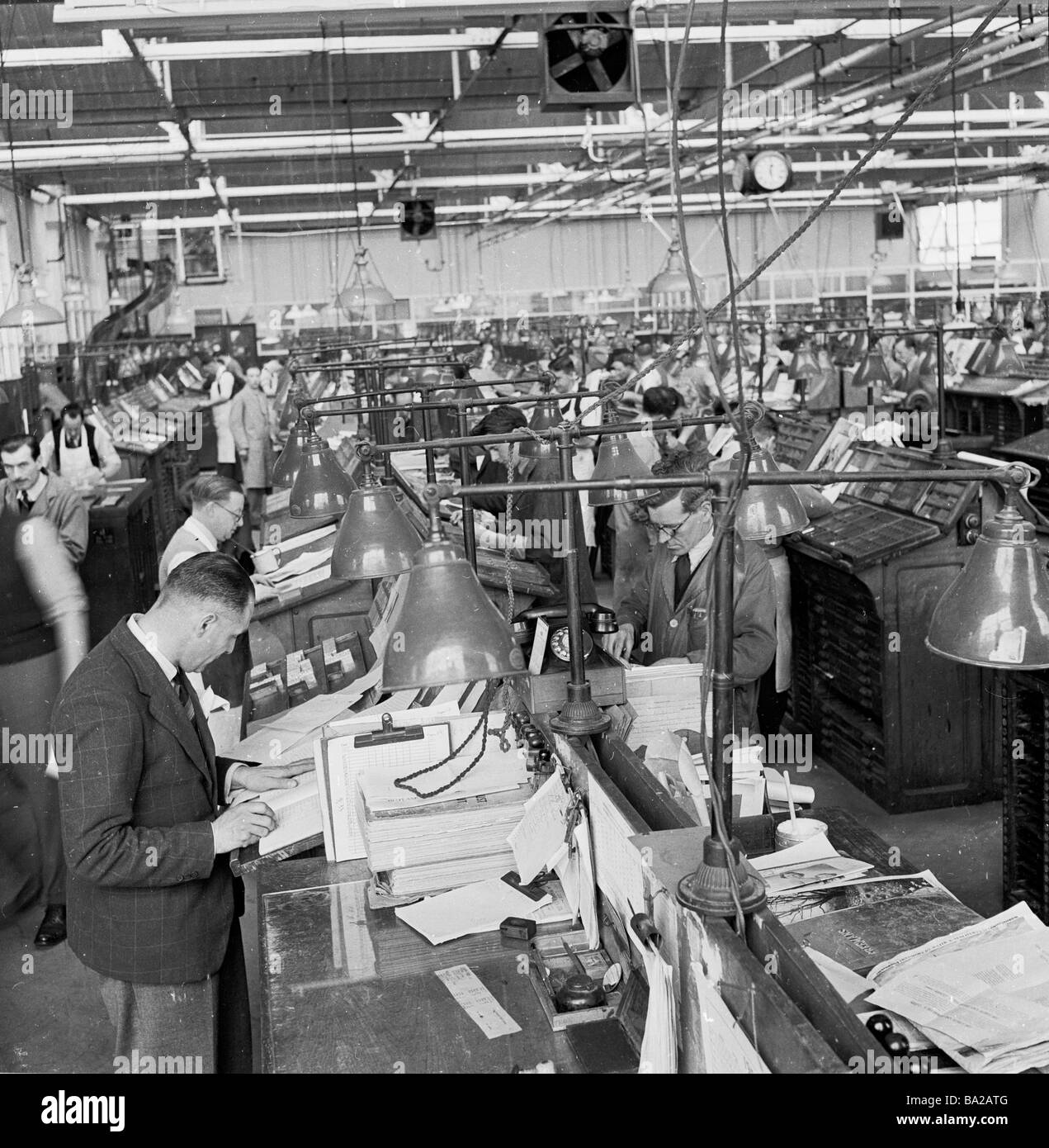 1950s, vista storica attraverso la sala di typesetting in una grande stampa opere, mostrando typesetters maschio o compositori in piedi woking, Inghilterra, Regno Unito. Foto Stock
