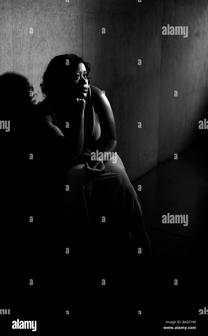 Immagine in bianco e nero di femmina nero appoggiato contro una parete a sognare di tempi migliori Foto Stock