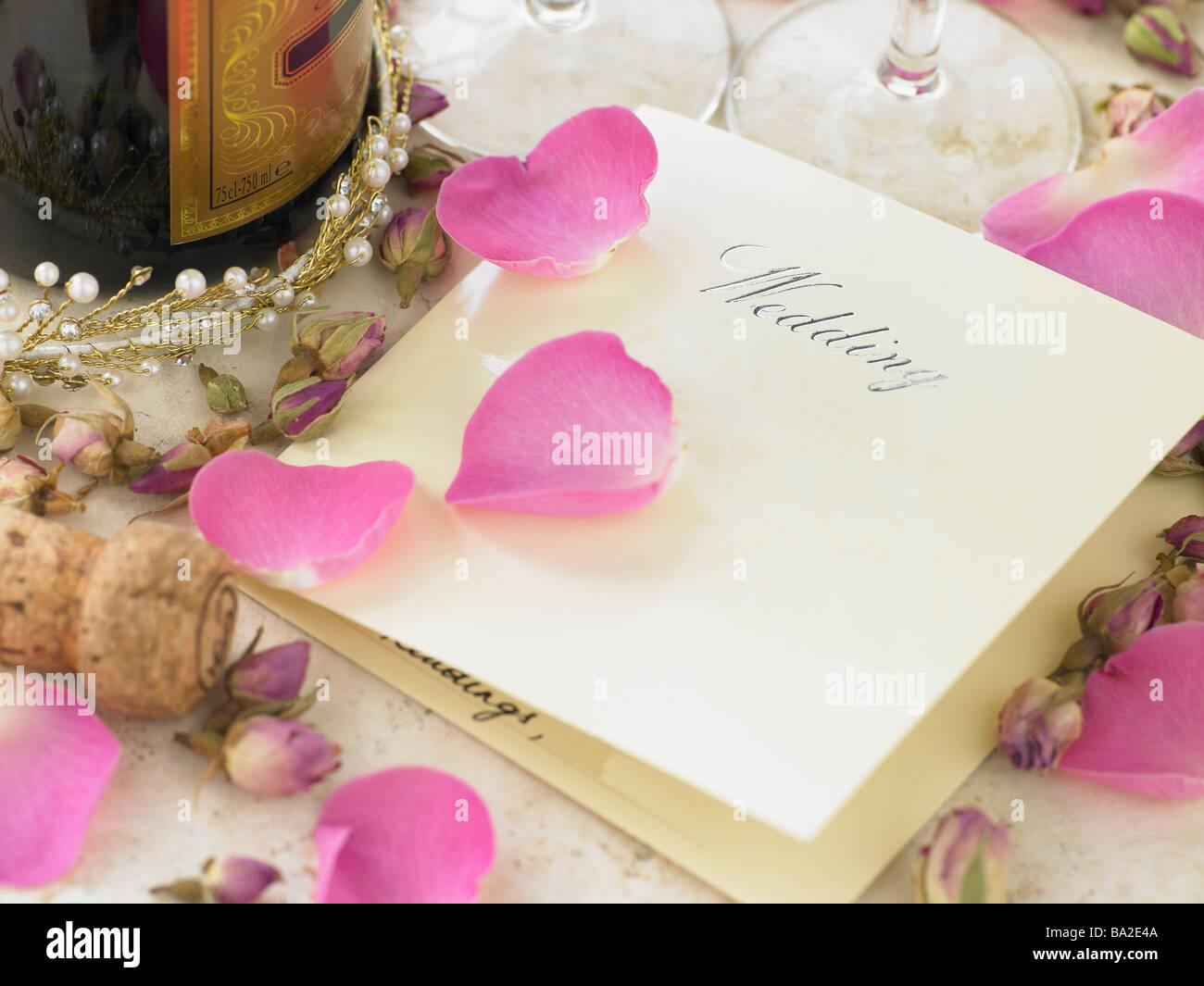 Invito a nozze accanto alla bottiglia di Champagne circondato da petali di fiori Foto Stock