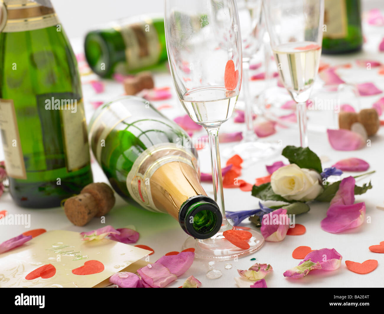 Svuotare le bottiglie di vino tra i petali di rose Foto Stock
