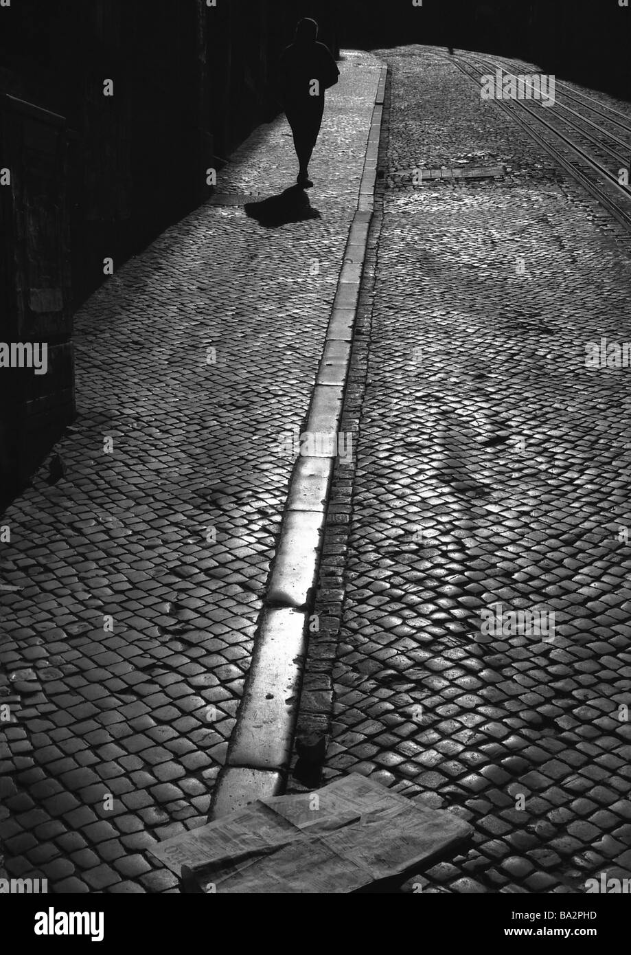 Street acciottolato donna va silhouette sera s/w marciapiede giornale quotidiano lastricata di persona lascia le persone pedone Foto Stock