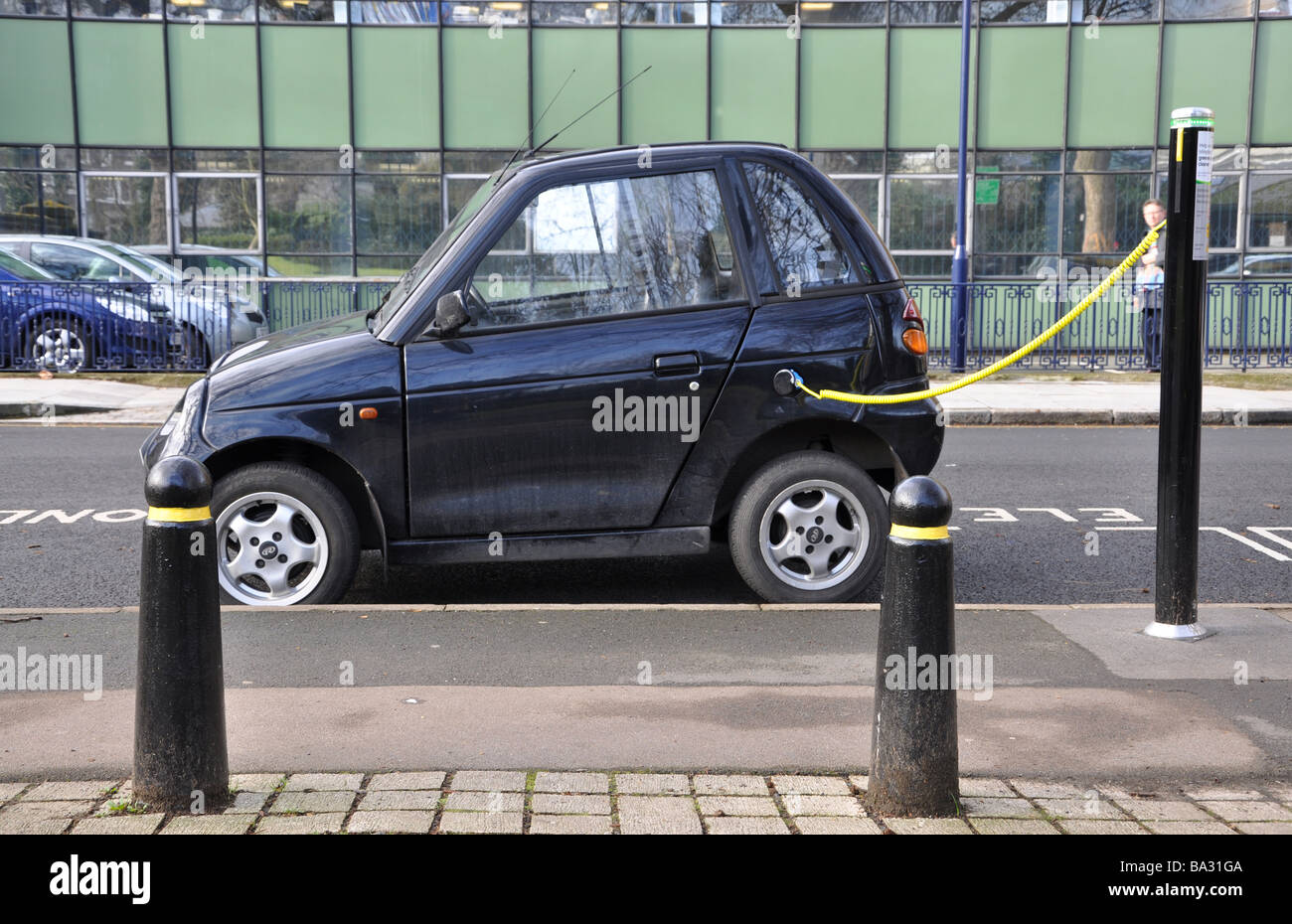 Auto elettrica essendo caricato con un cavo inserito in uno spazio di parcheggio Foto Stock