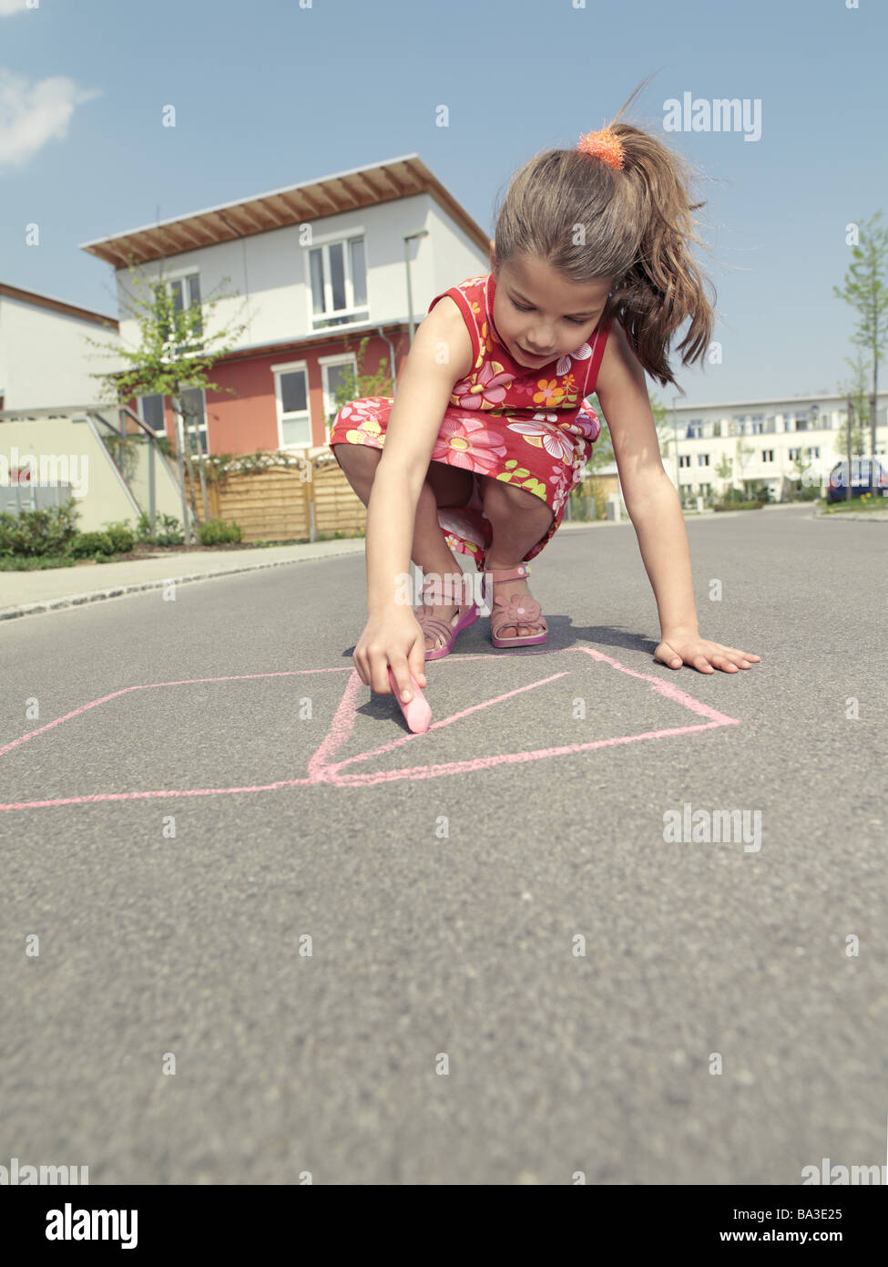 Ragazze crouch chalk scatole vernici di strada persone serie infanzia bambini 9 anni vestito estivo sandali con i capelli lunghi bruna Foto Stock