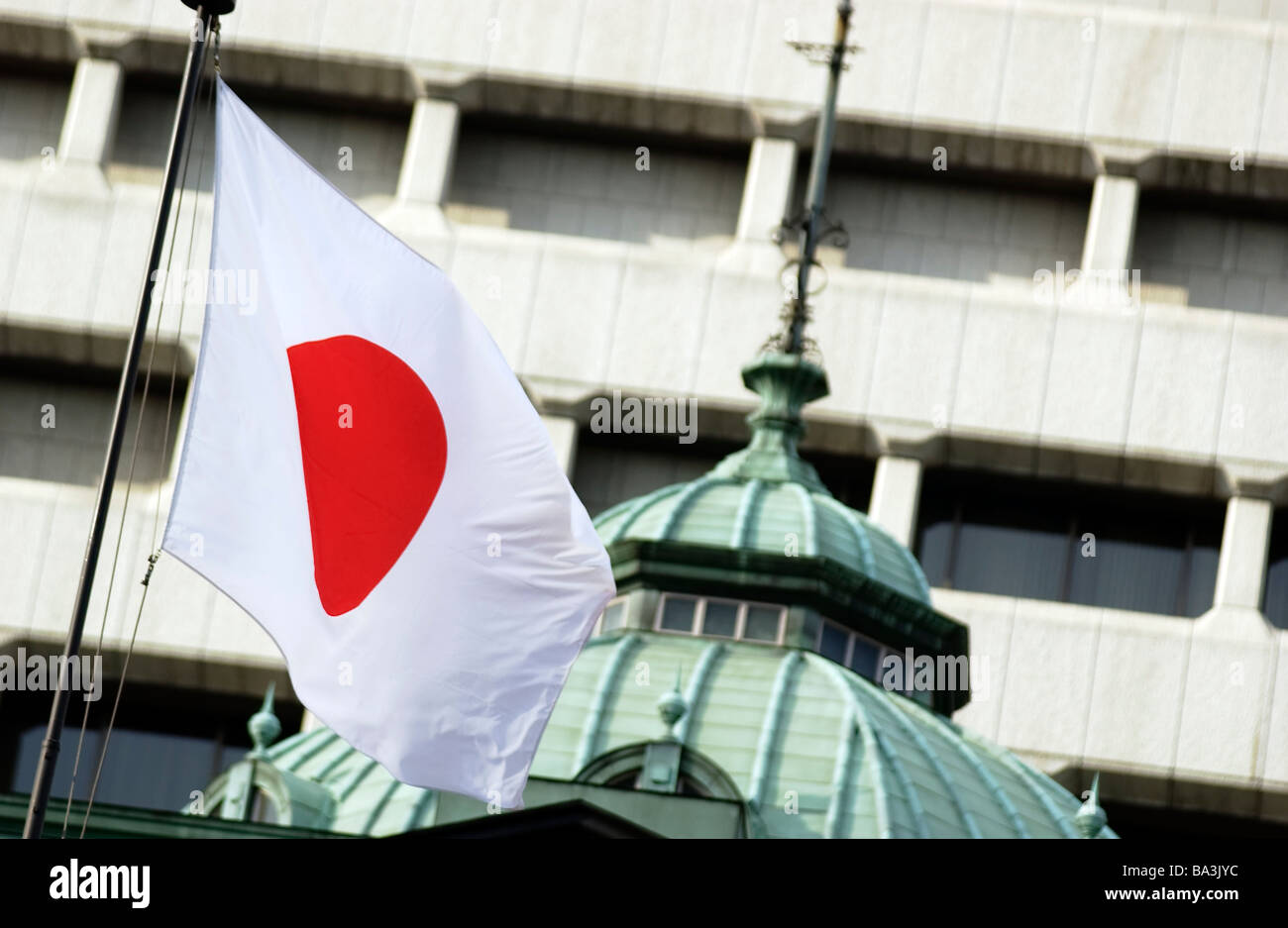Una bandiera giapponese la Hinomaru vola al di fuori della Banca del Giappone a Tokyo Foto Stock