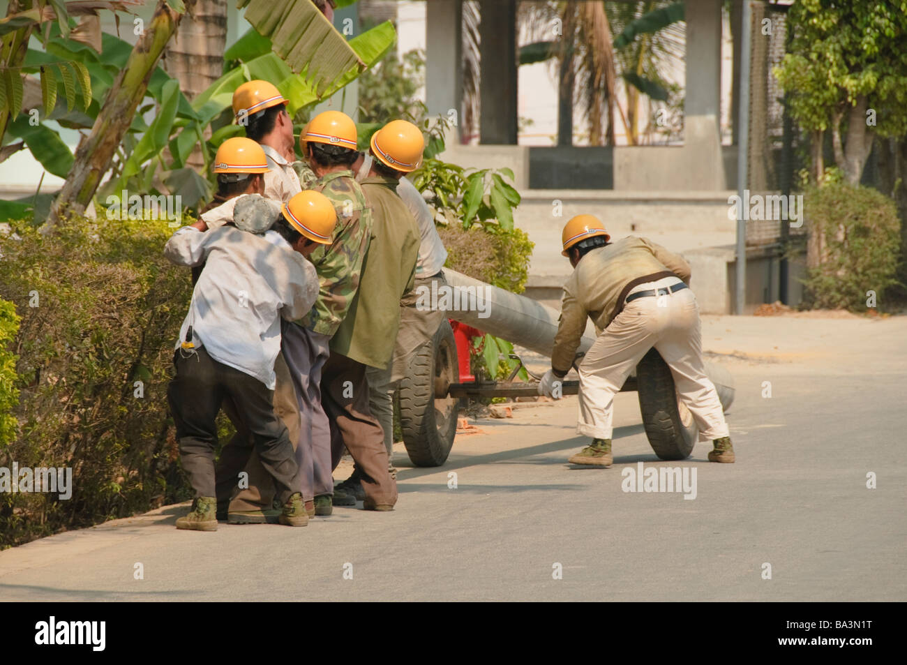 Operai di sollevamento di un tubo pesante in Yunnan in Cina Foto Stock