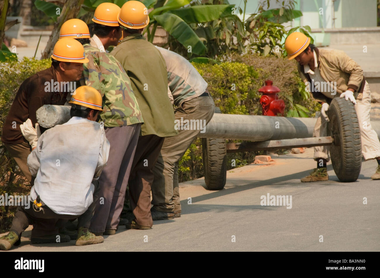 Operai di sollevamento di un tubo pesante in Yunnan in Cina Foto Stock