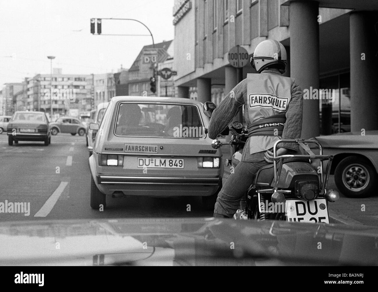 Negli anni settanta, foto in bianco e nero, scuola di pilotaggio, il traffico locale, allievo conducente su una moto corse dietro una scuola guida auto con istruttore di guida, D-Duisburg, Rhein Ruhr, Renania settentrionale-Vestfalia Foto Stock