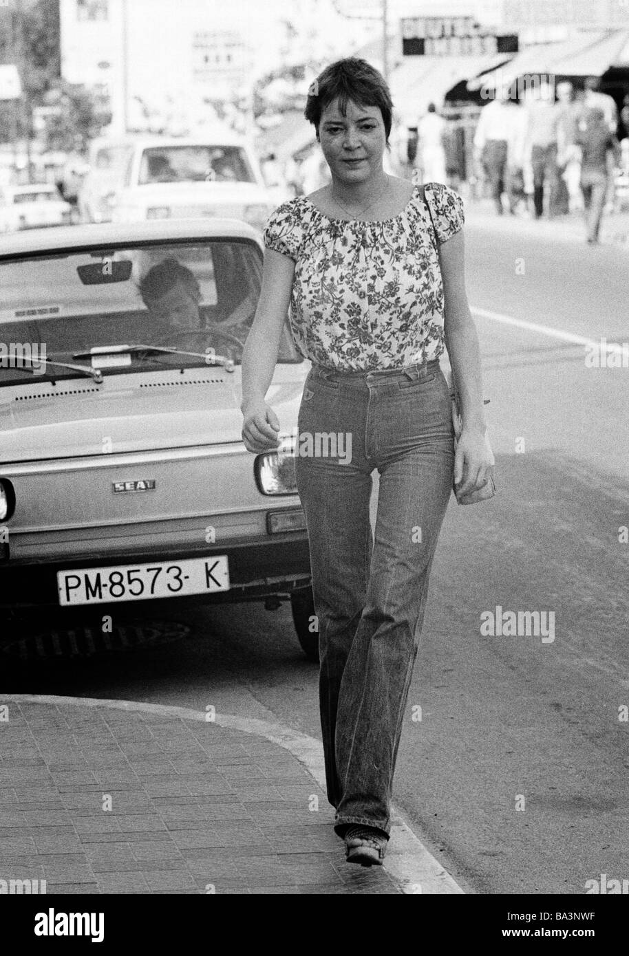 Negli anni settanta, foto in bianco e nero, persone, giovane donna sul marciapiede, camicetta, jeans pantaloni, parcheggio auto, di età compresa tra 22 a 28 anni, Isole Baleari Spagna, Mallorca, Palma de Maiorca Foto Stock