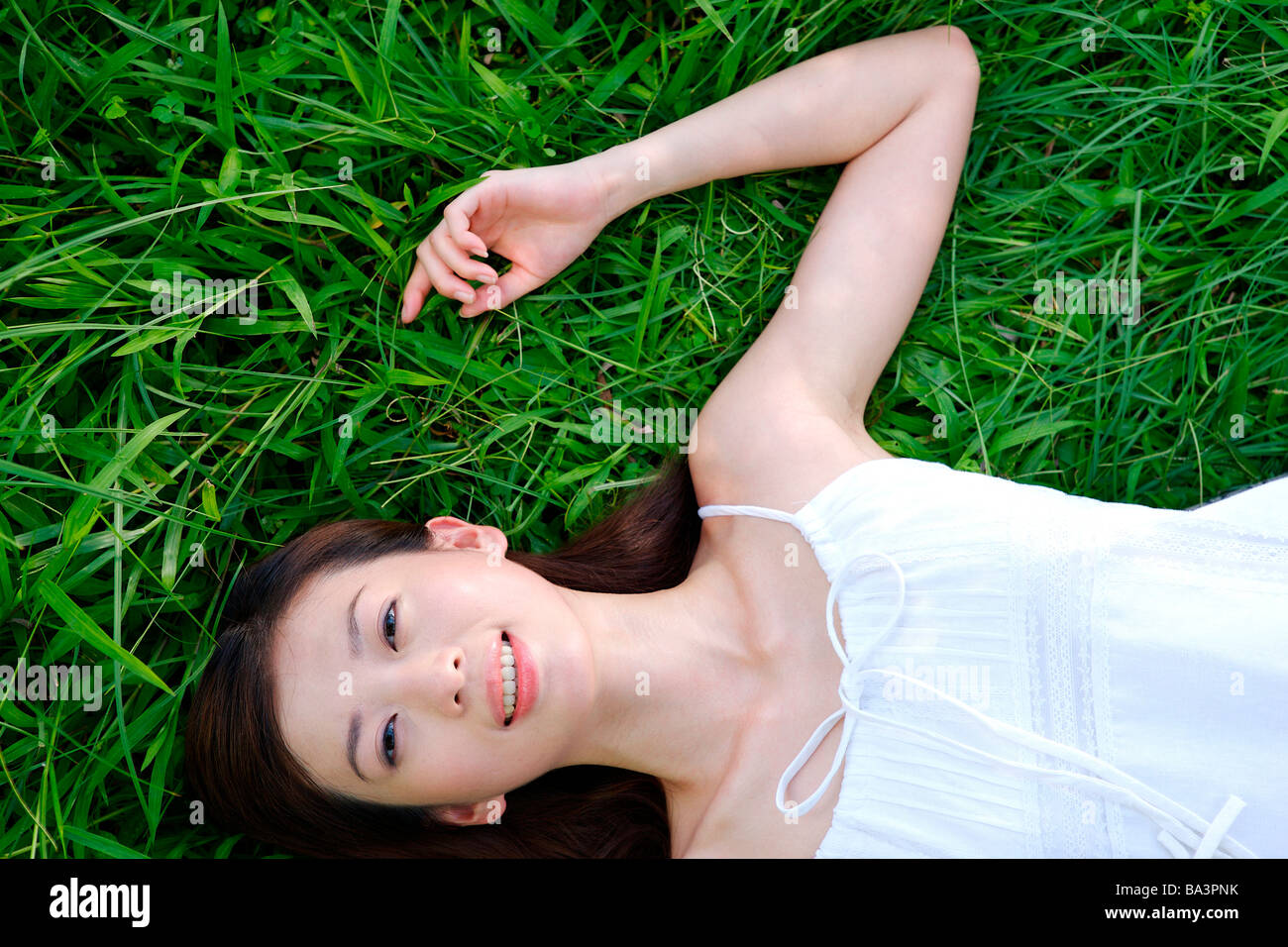 Giovane donna sdraiata su erba con sorridente guardando la fotocamera Foto Stock
