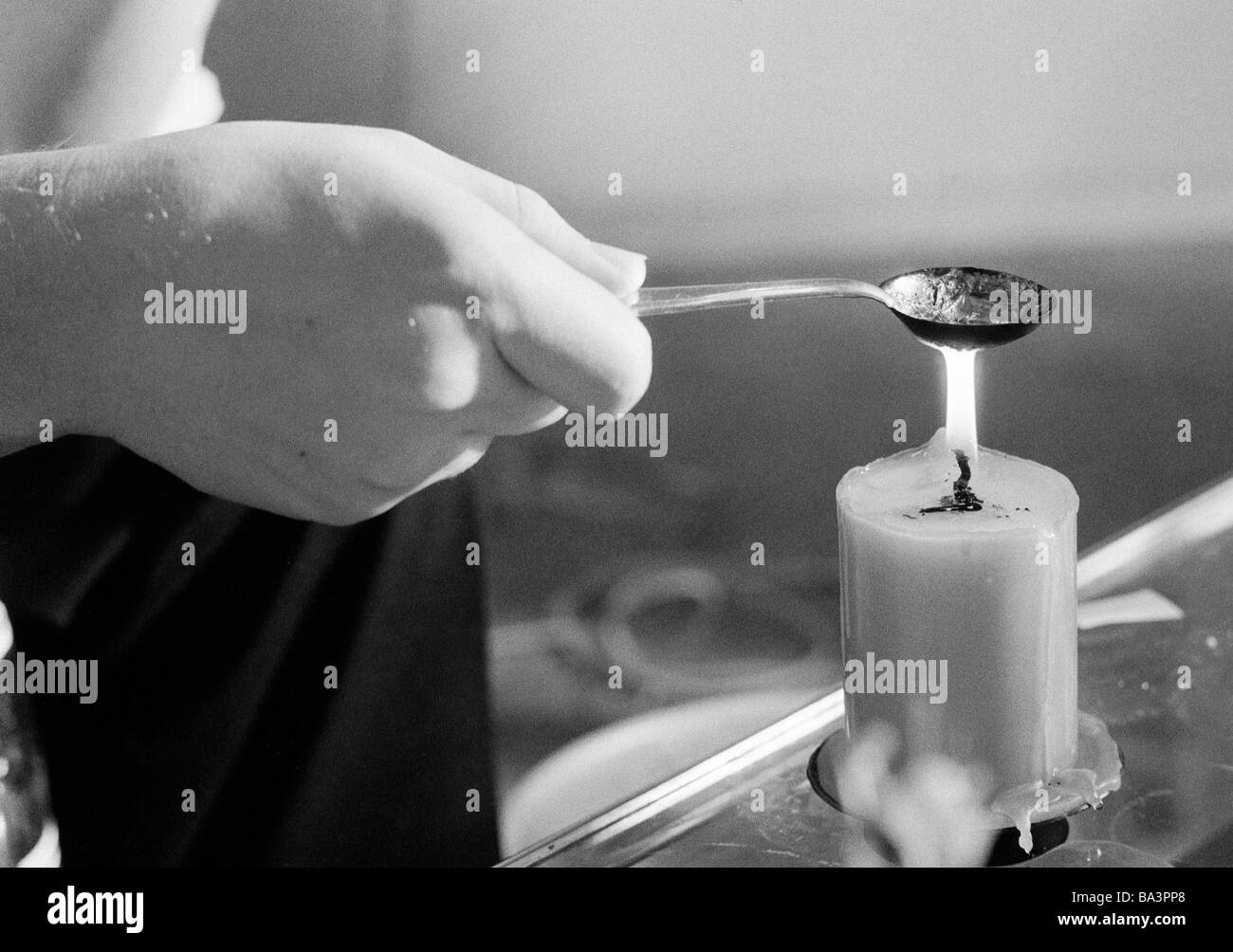 Negli anni settanta, foto in bianco e nero, la gente, la notte della Vigilia di Capodanno, per celebrare il Nuovo Anno, simbolici soothsay, piombo-VERSAMENTO, mano trattiene un cucchiaio contenente plumb su una candela accesa Foto Stock