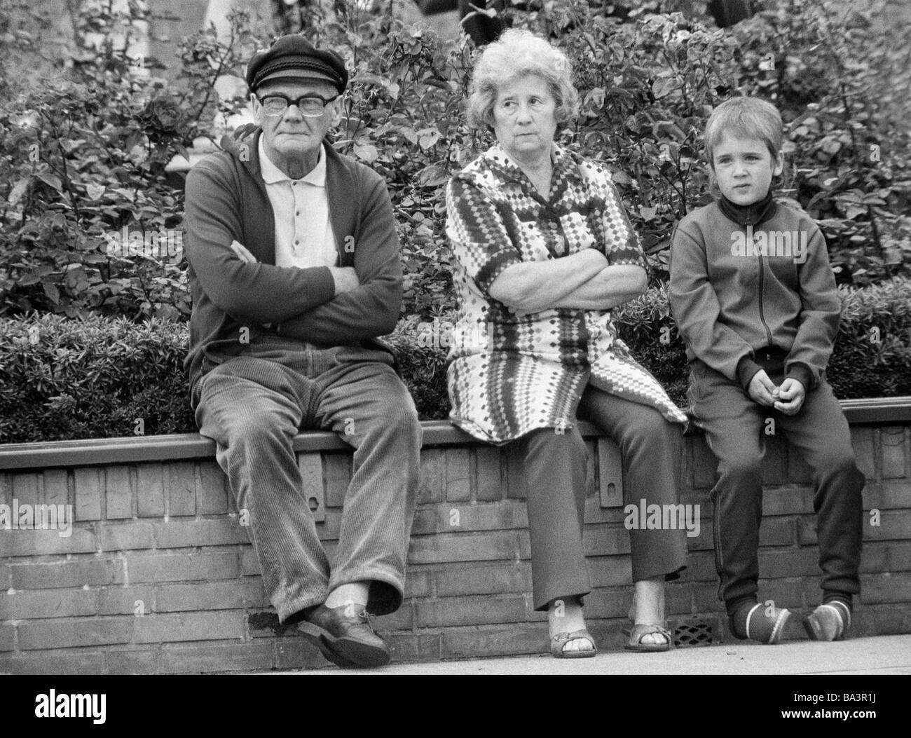 Negli anni settanta, foto in bianco e nero, persone, coppia di anziani e nipote di sedersi su un muro, di età compresa tra 60 a 70 anni di età compresa tra 8 e 11 anni Foto Stock