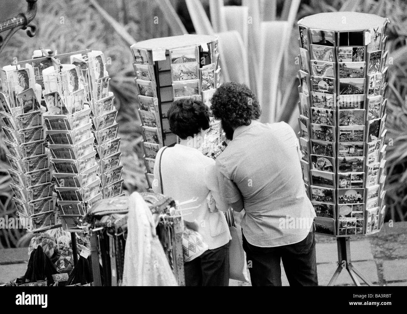 Ottanta, foto in bianco e nero, la gente giovane coppia sceglie le cartoline in mapstands, vacanze Spagna Isole Canarie, Canarie, Tenerife, di età compresa tra 25 a 35 anni Foto Stock