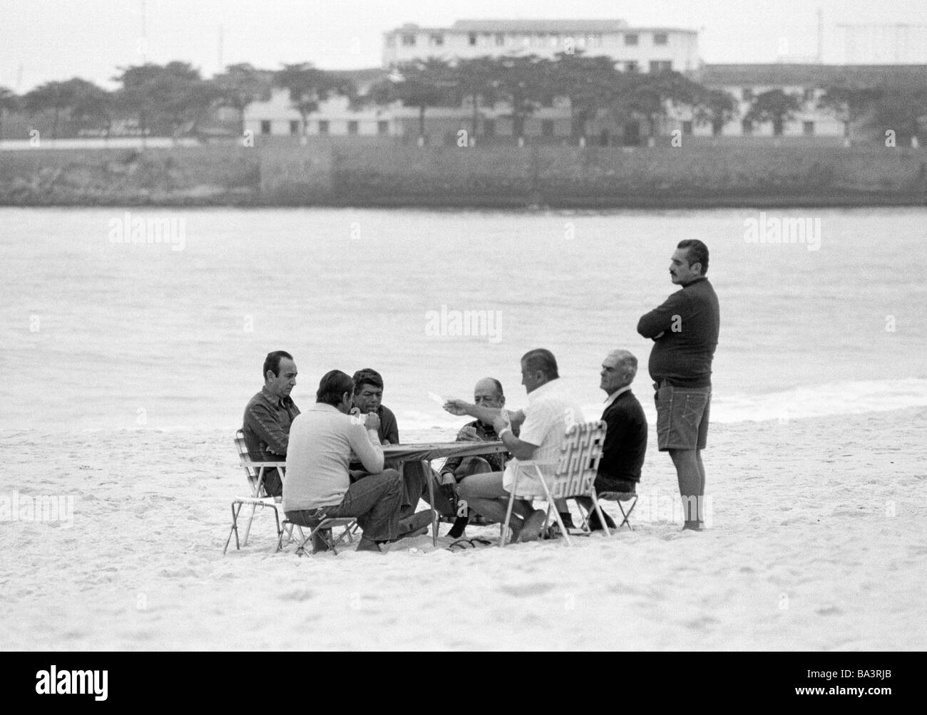 Ottanta, foto in bianco e nero, persone, alcuni uomini seduti ad un tavolo sulla spiaggia di Copacabana e giocare a carte, di età compresa tra i 50 e i 70 anni, del Brasile e di Rio de Janeiro Foto Stock