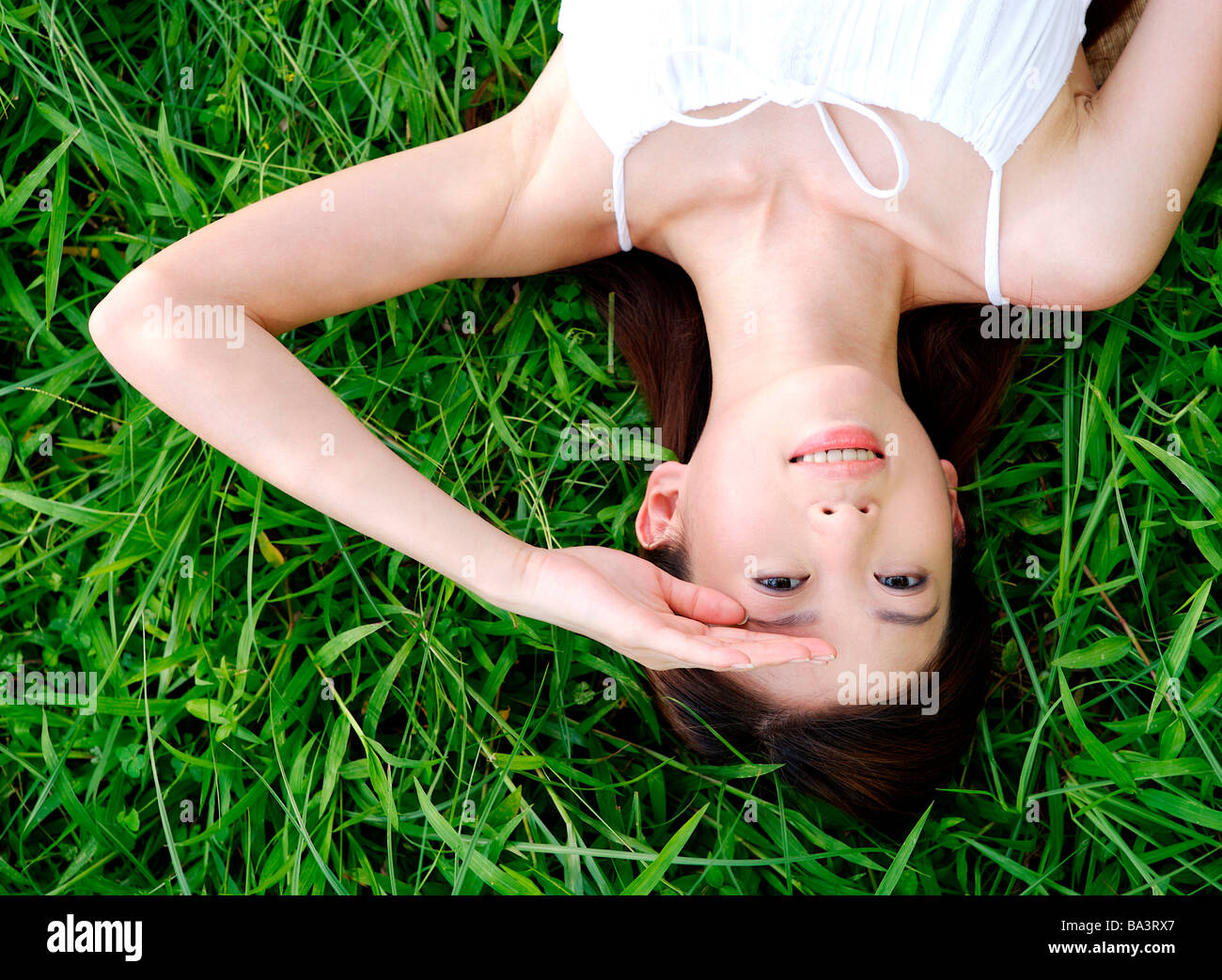 Giovane donna sdraiata su erba con sorridente cercando Foto Stock