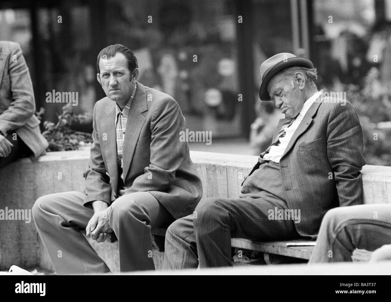 Negli anni settanta, foto in bianco e nero, persone, uomo anziano si siede su una panchina e dorme uomo giovane si siede emotionless accanto a lui, di età compresa tra 40 a 50 anni di età compresa tra 65 a 70 anni Foto Stock