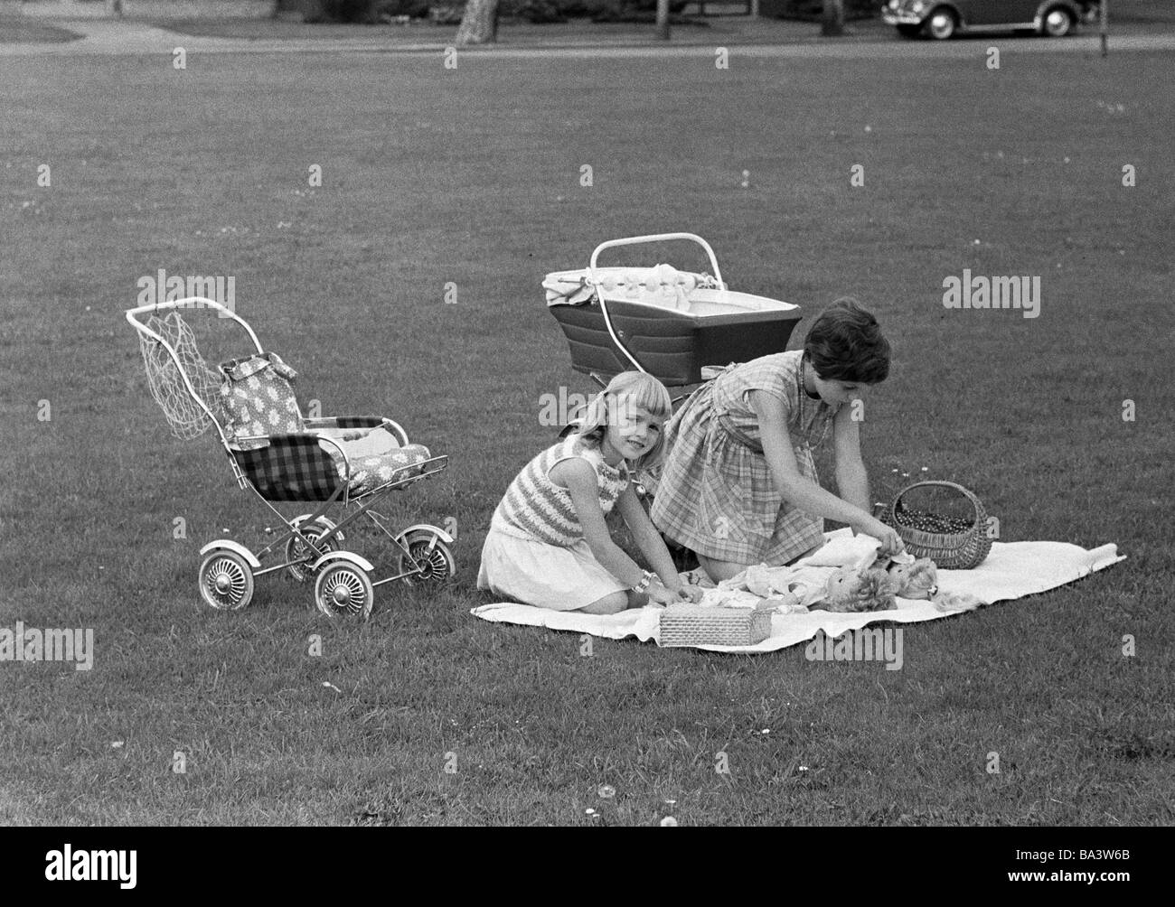 Anni sessanta, foto in bianco e nero, persone, bambini, due bambine giocando su un prato con bambole e carrelli di bambola, di età compresa tra i 3 e i 5 anni di età compresa da 6 a 10 anni Foto Stock