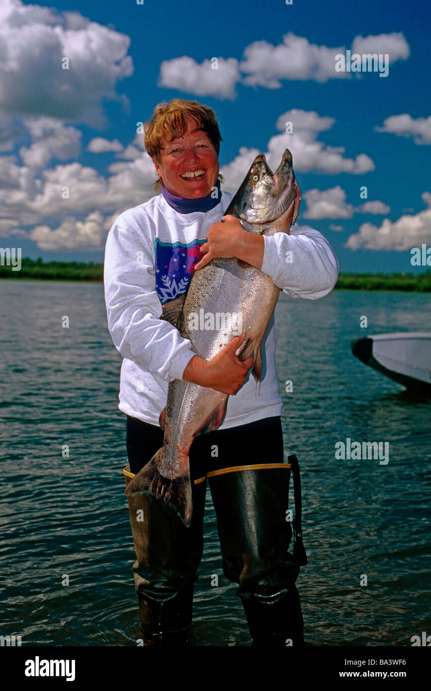 Fisherwoman abbraccia gran re salmone lungo la riva del fiume Nushagak Southwest AK Estate Foto Stock