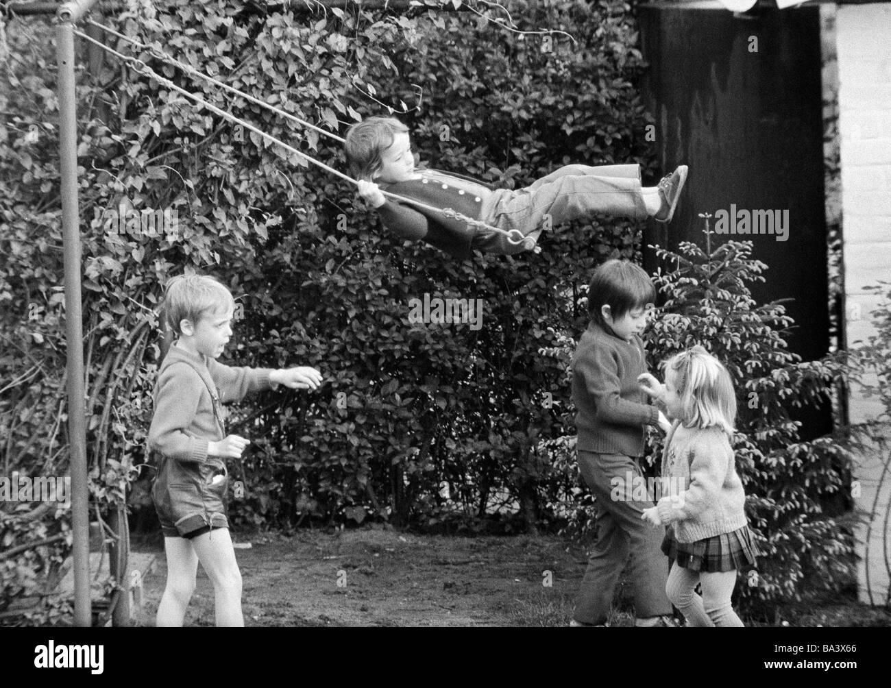 Negli anni settanta, foto in bianco e nero, persone, bambini, due ragazze e due ragazzi piccoli, swing-set, parco giochi per bambini di età compresa tra 4 e 8 anni Foto Stock
