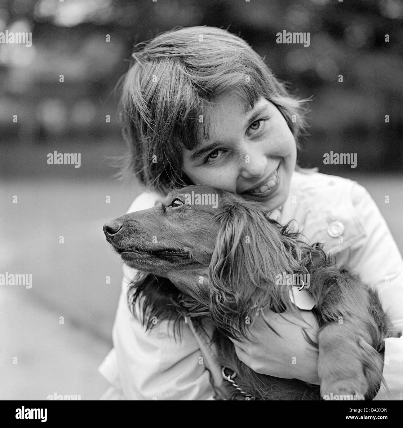 Negli anni settanta, foto in bianco e nero, umana e animale, giovane ragazza di coccole con un bassotto, di età compresa tra i 10 e i 14 anni, cane domestico, Canis lupus familiaris Foto Stock