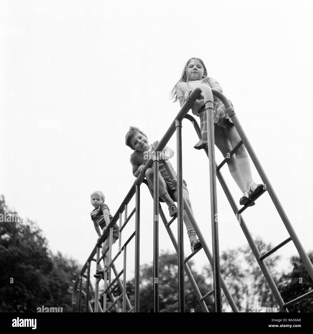 Negli anni settanta, foto in bianco e nero, persone, bambini, bambina e due ragazzi su una scimmia bar, parco giochi per bambini di età compresa da 4 a 7 anni Foto Stock