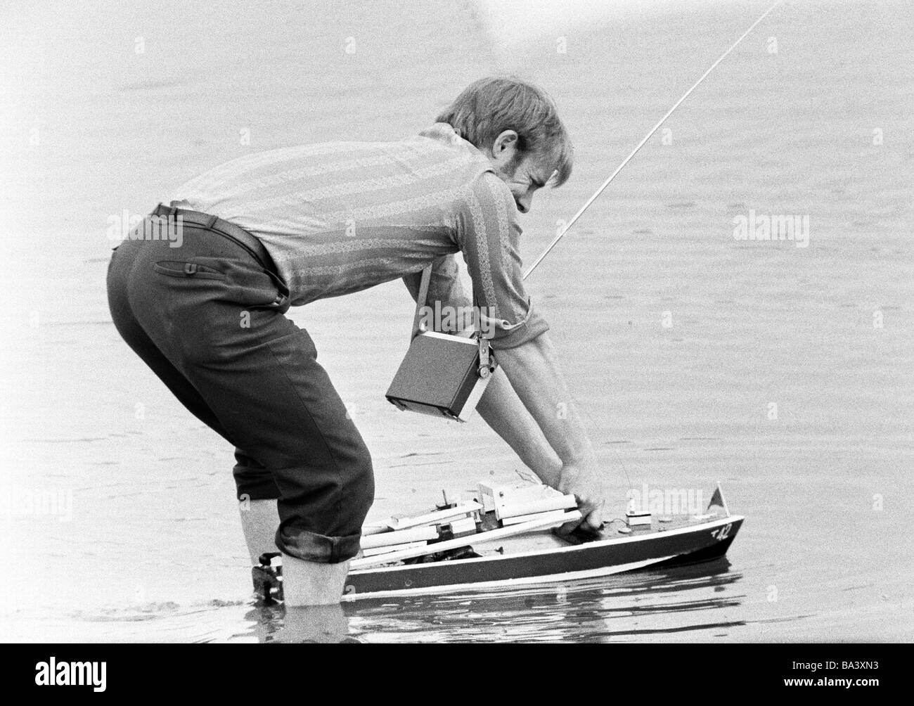 Negli anni settanta, foto in bianco e nero, persone, l uomo sta con i suoi piedi in acqua iniziando il suo modello di nave, trasmettitore portatile, trasmettitore portatile, radio trasmettitore, il telecontrollo, hobby, di età compresa tra 30 a 40 anni Foto Stock