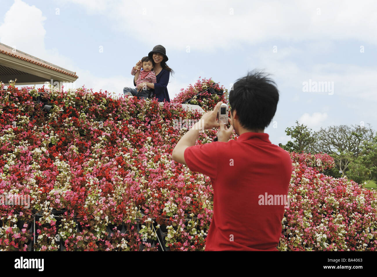 Padre tenendo fotografia della sua famiglia sul balcone Foto Stock