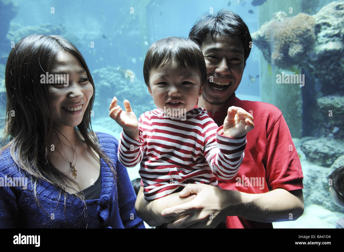 Coppia giapponese con il suo bambino guardando aquarium Foto Stock