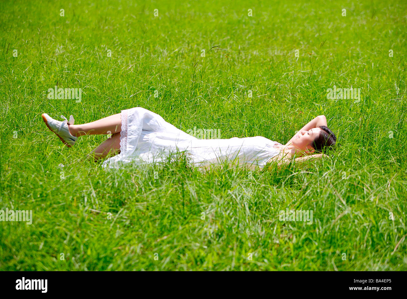 Giovane donna sdraiata su erba vista laterale Foto Stock