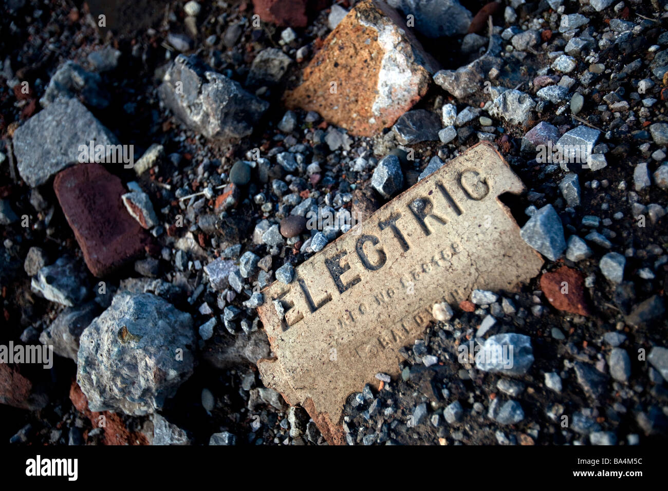 Un segno di avvertimento di elettricità impresso in un mattone su una fabbrica in disuso sito England Regno Unito Foto Stock