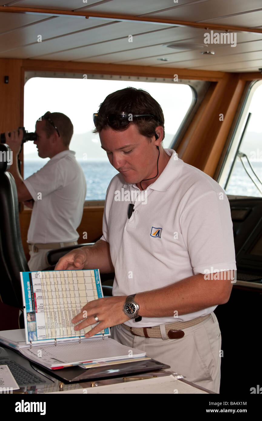 Capitano controllando il registro sul ponte di super yacht "grandi" di Aron, comandante mantenendo il look out con il binocolo Foto Stock