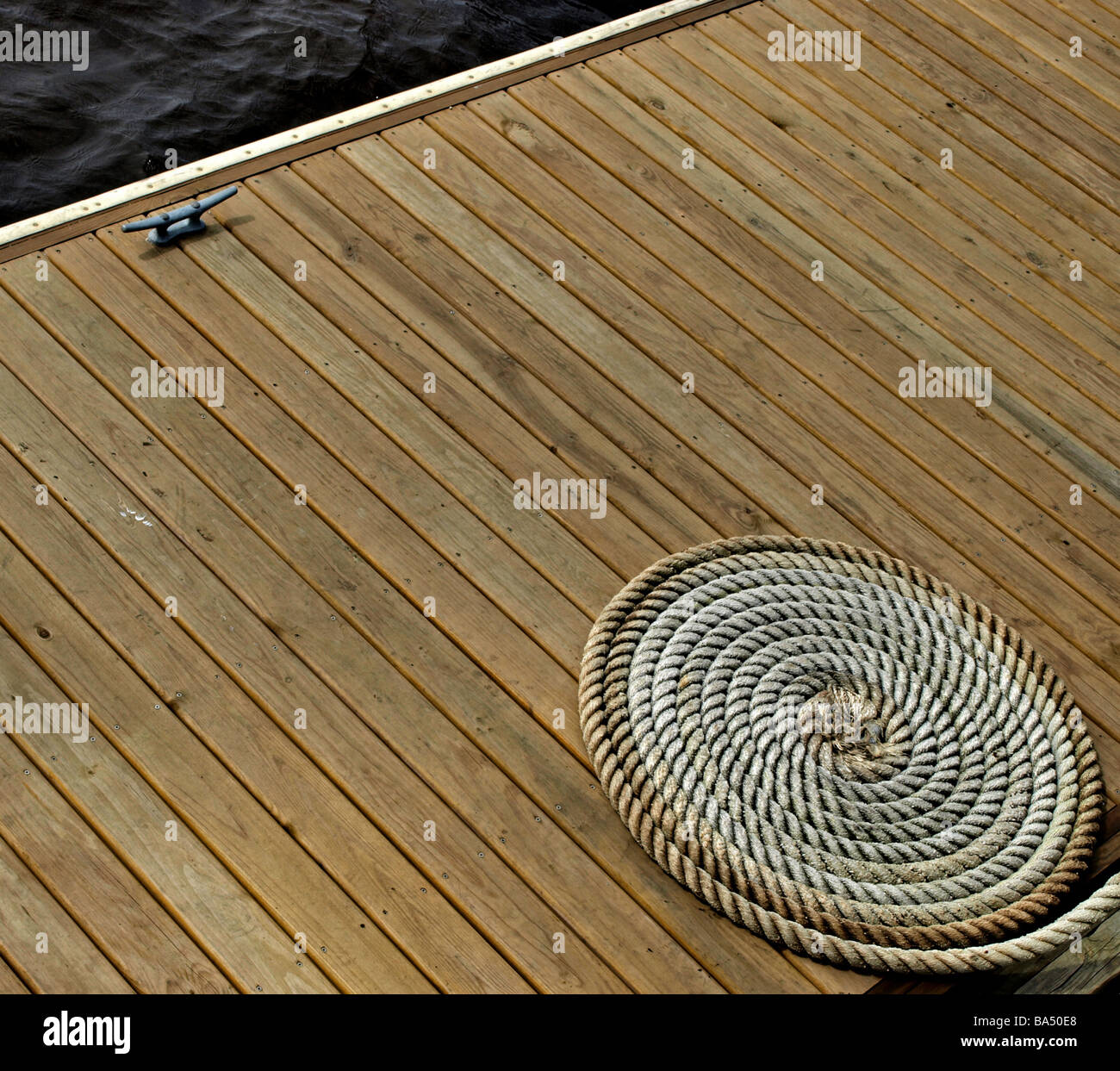 Ponte di legno sul fiume con corda avvolto a spirale e tie-up gancio, deck è più schede e geometrico contro il cerchio della corda Foto Stock
